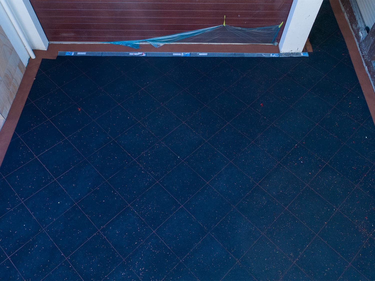 Close view of Black Sand Covercrete with fine coloured flecks, red Stencil lines and a red border along the garage door.