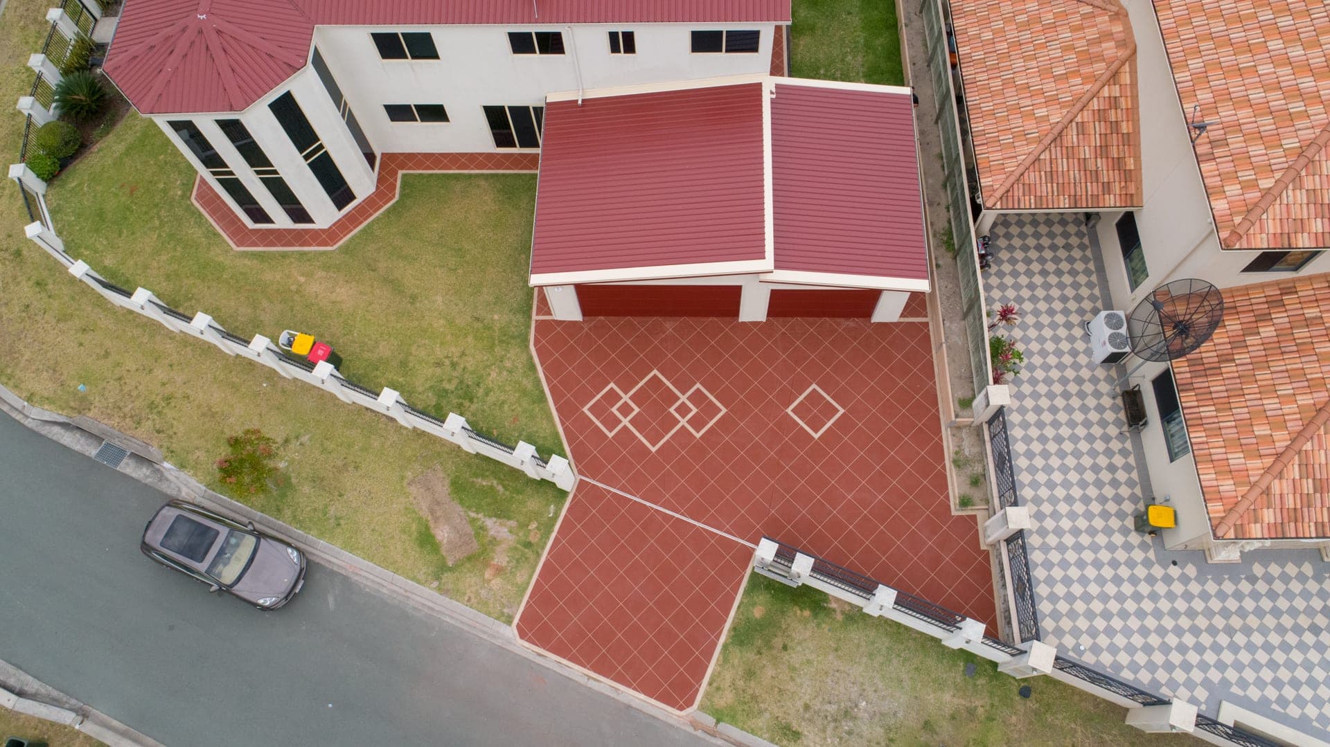 Drone view of a home in Stretton with a double driveway in Orange Brick Covercrete, an angled-square Stencil, cream borders and diamond feature panels in front of the garage.