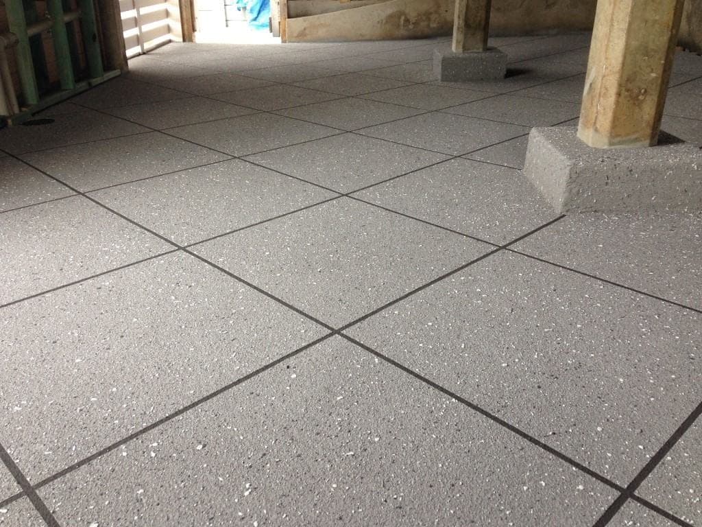 Speckled grey Covercrete with dark angled-square Stencil lines under a raised house, also covering the footings of the timber posts.
