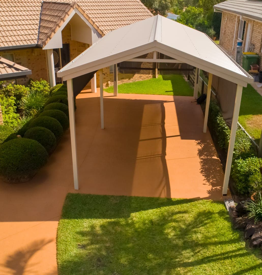 Sunburnt Orange Covercrete under a carport and across the driveway, seen from above the front lawn.