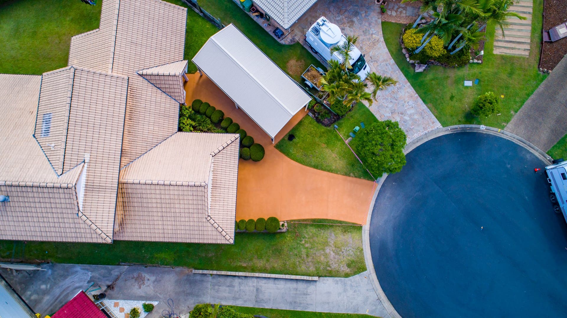 Drone view straight down on a home with its driveway and carport in a plain layer of Sunburnt Orange Covercrete.